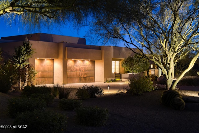 pueblo-style house with an attached garage and stucco siding