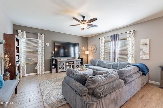 living room with a ceiling fan, light wood-style flooring, and baseboards