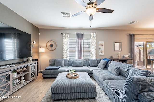 living area featuring light wood-style flooring, visible vents, and ceiling fan