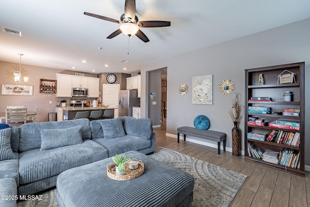 living area featuring light wood finished floors, baseboards, visible vents, a ceiling fan, and recessed lighting