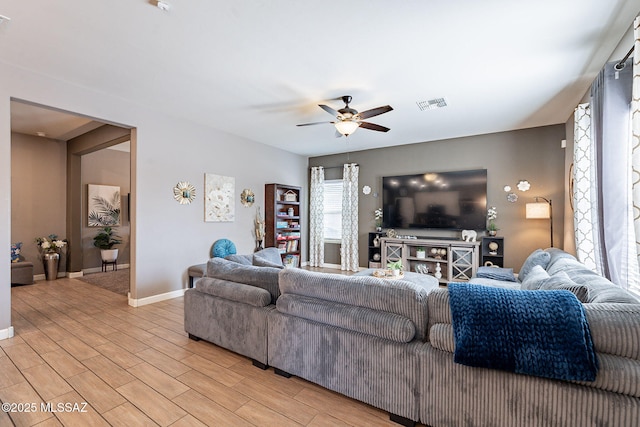 living area with a ceiling fan, visible vents, light wood-style flooring, and baseboards