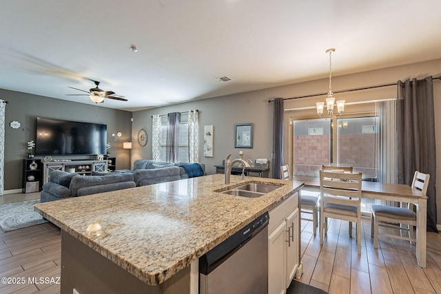 kitchen featuring a sink, white cabinets, stainless steel dishwasher, a center island with sink, and pendant lighting
