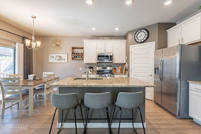 kitchen featuring appliances with stainless steel finishes, wood finish floors, white cabinets, and a sink