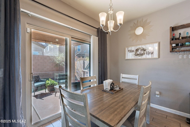dining space featuring baseboards, a notable chandelier, and wood finished floors