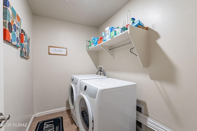 clothes washing area with laundry area, washing machine and dryer, light wood-style flooring, and baseboards