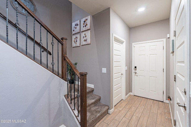 foyer featuring light wood-type flooring, stairway, and baseboards