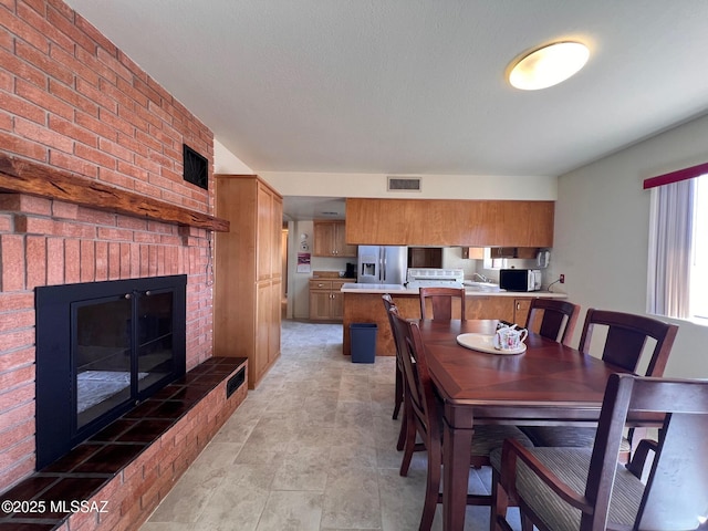 dining room featuring a brick fireplace and visible vents