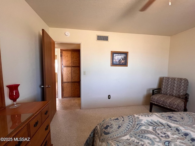 bedroom featuring light carpet, a textured ceiling, and visible vents