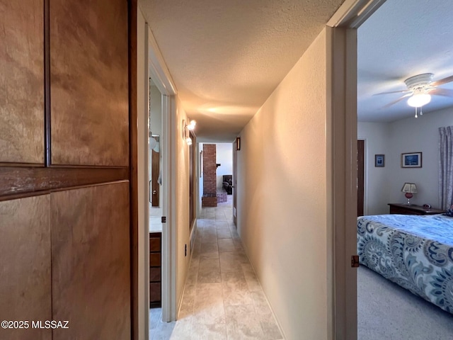 hall featuring a textured ceiling and a textured wall