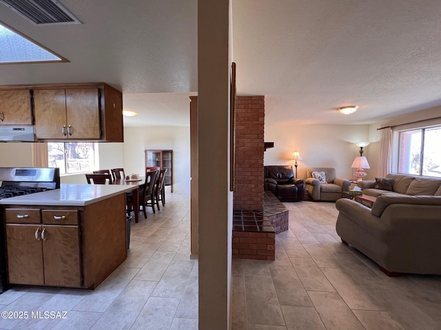 kitchen with visible vents, open floor plan, stainless steel gas range, light countertops, and exhaust hood