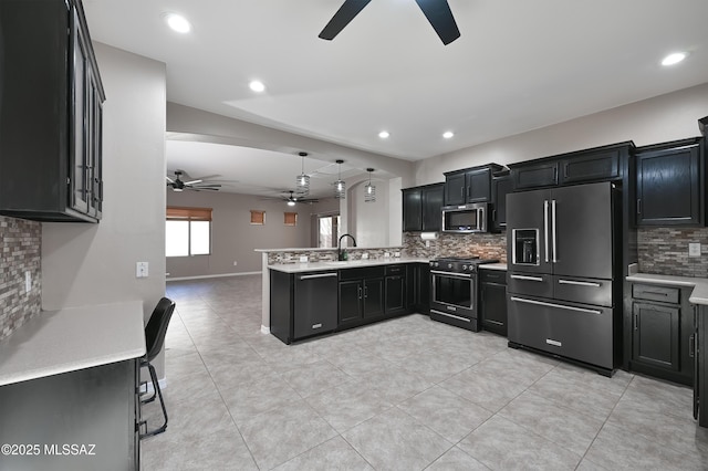 kitchen with a peninsula, appliances with stainless steel finishes, light countertops, and dark cabinetry