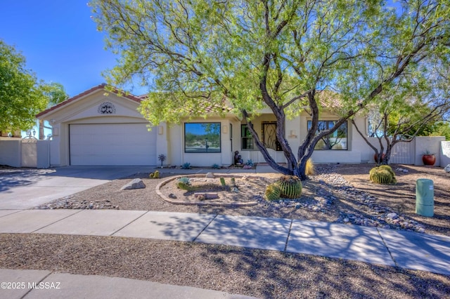 ranch-style house featuring an attached garage, driveway, fence, and stucco siding