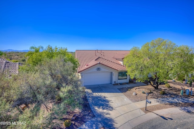 mediterranean / spanish house featuring driveway, a tile roof, a garage, and stucco siding