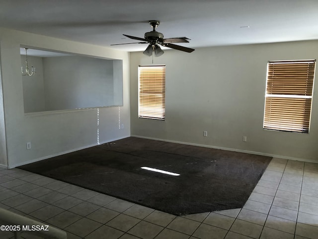 unfurnished room featuring tile patterned flooring, baseboards, and ceiling fan with notable chandelier