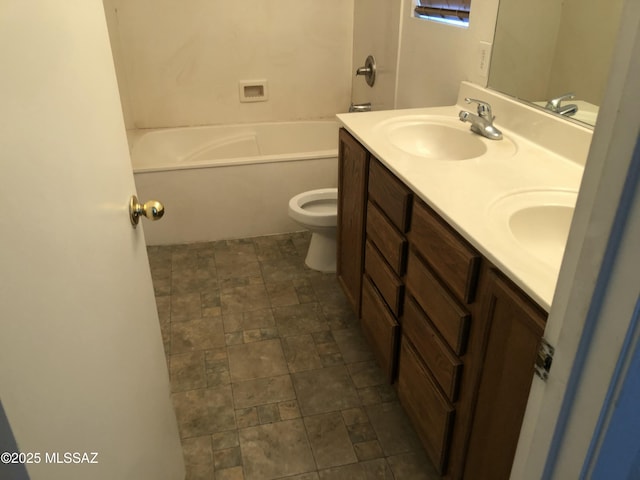 bathroom featuring stone finish flooring, a sink, toilet, and double vanity