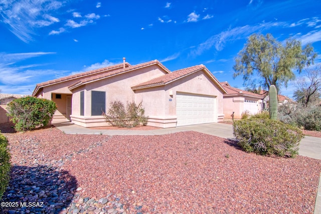 view of front of house with driveway, an attached garage, a tile roof, and stucco siding