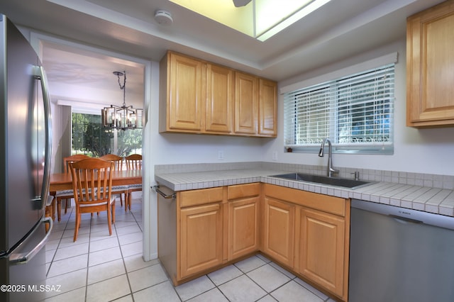 kitchen featuring light tile patterned floors, appliances with stainless steel finishes, a sink, and tile counters