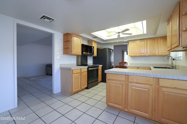 kitchen with a skylight, visible vents, light brown cabinets, a sink, and range with electric cooktop