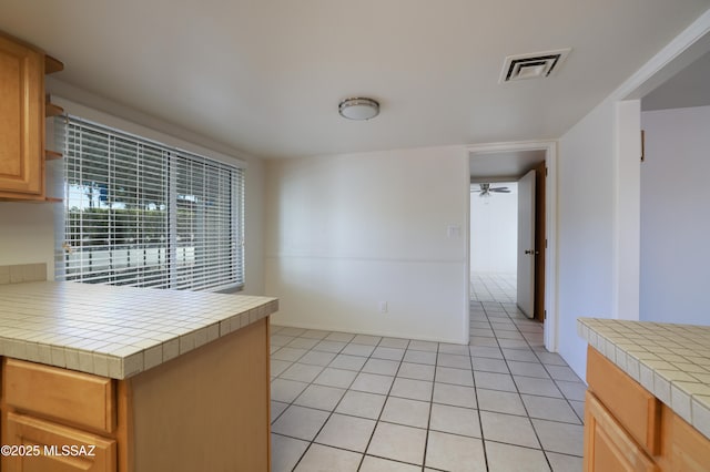 kitchen featuring a ceiling fan, visible vents, tile countertops, and light tile patterned flooring