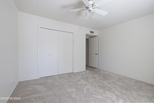 unfurnished bedroom with light carpet, ceiling fan, visible vents, and a closet