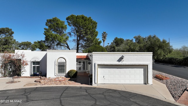 mediterranean / spanish-style home with a garage, driveway, a tile roof, and stucco siding