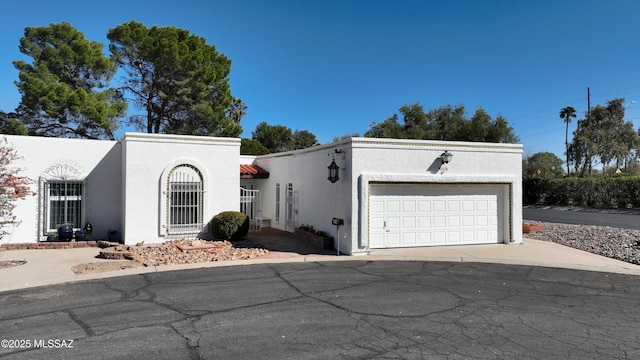 view of front of home featuring driveway, an attached garage, and stucco siding