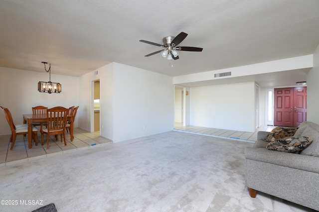 living room with light carpet, light tile patterned floors, visible vents, and ceiling fan with notable chandelier