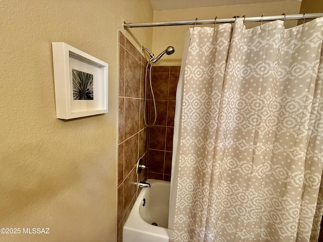 bathroom featuring a textured wall and shower / tub combo with curtain