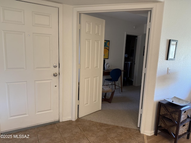 hallway with dark carpet and dark tile patterned flooring