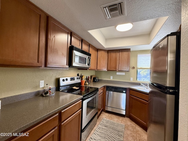 kitchen featuring stainless steel appliances, a raised ceiling, visible vents, a sink, and a textured ceiling