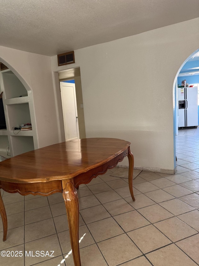 5017 S 11th Ave, Tucson, AZ 85706 - dining space with light tile patterned flooring, a textured ceiling, arched walkways, and baseboards