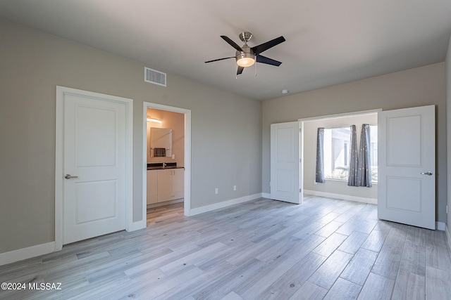 unfurnished bedroom featuring a ceiling fan, baseboards, visible vents, ensuite bathroom, and light wood-type flooring