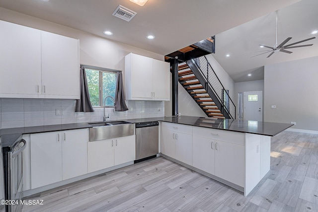 kitchen featuring visible vents, a peninsula, a sink, dishwasher, and dark countertops