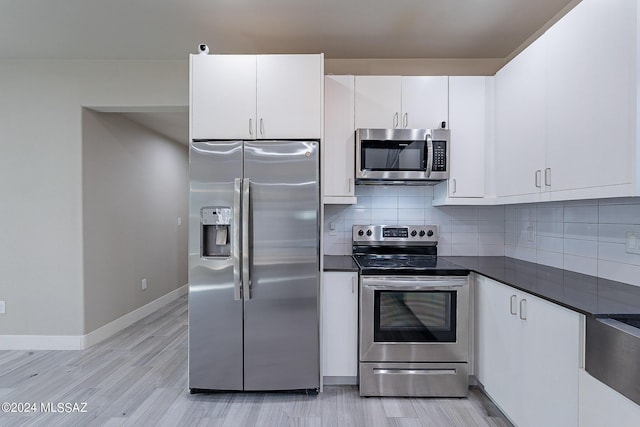 kitchen featuring baseboards, stainless steel appliances, white cabinetry, dark countertops, and backsplash