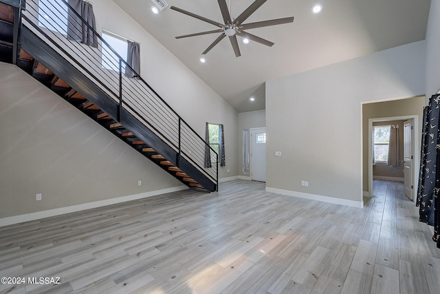 unfurnished living room with light wood finished floors, baseboards, stairway, recessed lighting, and high vaulted ceiling