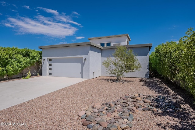 view of front facade featuring stucco siding, driveway, a garage, and fence