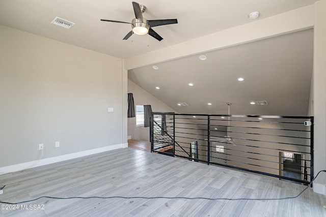 spare room with visible vents, a ceiling fan, wood finished floors, baseboards, and vaulted ceiling