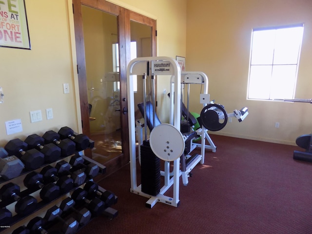 workout room with dark carpet and baseboards
