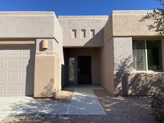 property entrance featuring a garage and stucco siding