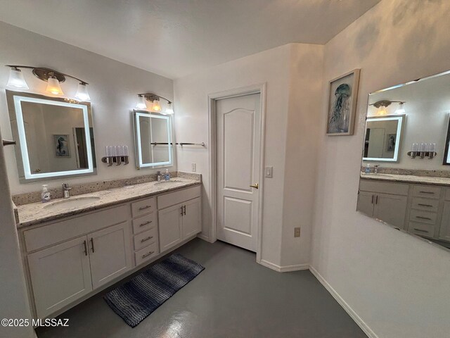 bathroom with baseboards, double vanity, a sink, and finished concrete floors