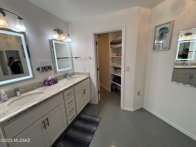 bathroom featuring a sink, a walk in closet, and double vanity