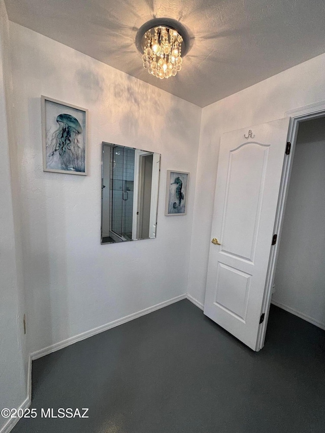 empty room featuring baseboards and a chandelier