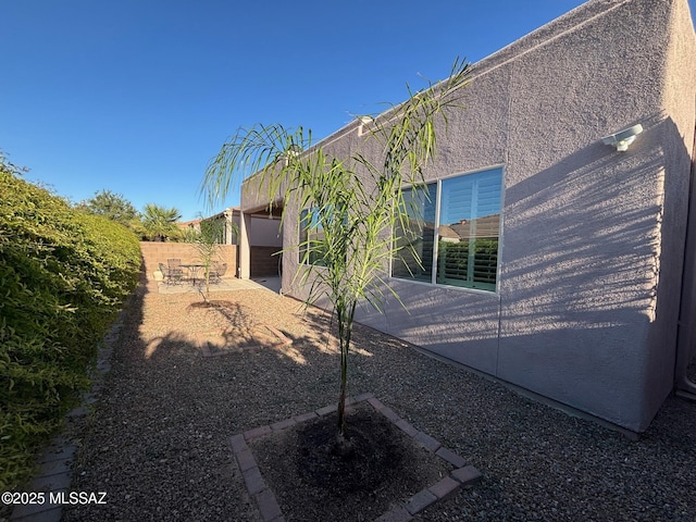 rear view of house featuring fence, stucco siding, and a patio area