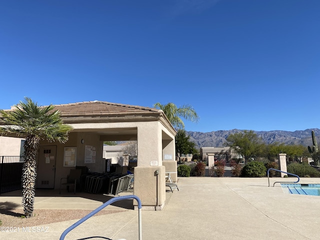 community pool with a patio area, a mountain view, and fence