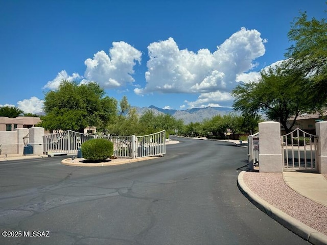 view of street with a gate, a gated entry, and curbs
