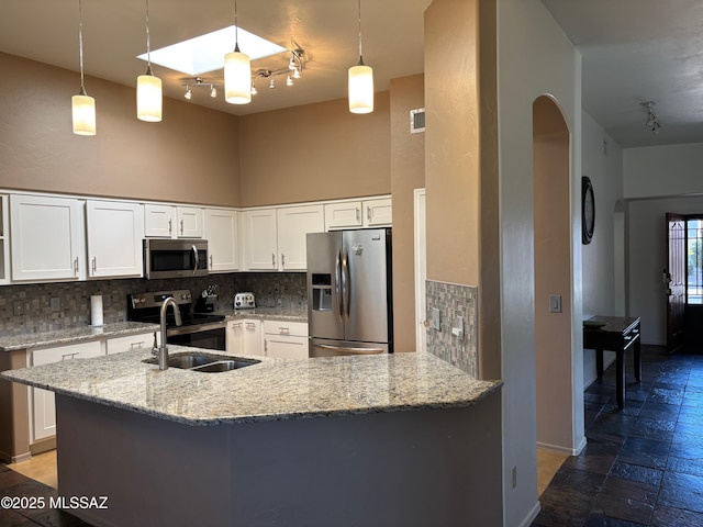 kitchen featuring backsplash, arched walkways, rail lighting, and appliances with stainless steel finishes
