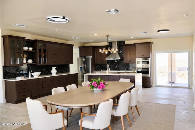 1077 Avenida Aire, Rio Rico, AZ 85648 - kitchen featuring appliances with stainless steel finishes, wall chimney exhaust hood, dark brown cabinets, tasteful backsplash, and recessed lighting