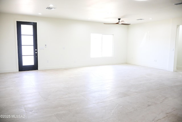 spare room featuring visible vents, a ceiling fan, and baseboards