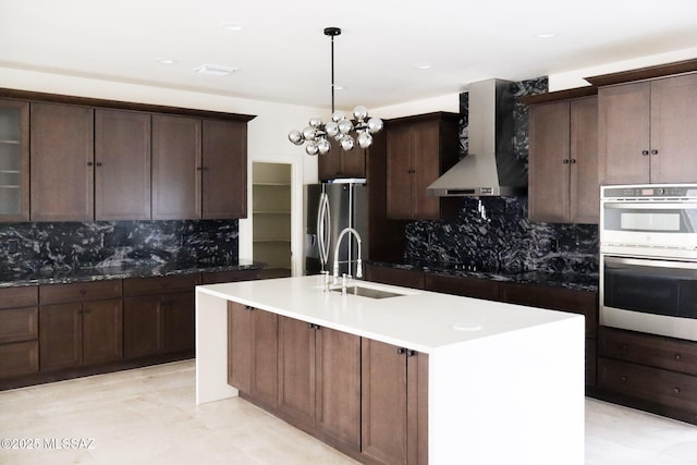 kitchen with a sink, backsplash, wall chimney exhaust hood, and appliances with stainless steel finishes