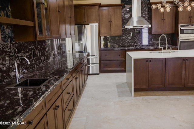 kitchen featuring a sink, decorative backsplash, appliances with stainless steel finishes, and wall chimney range hood